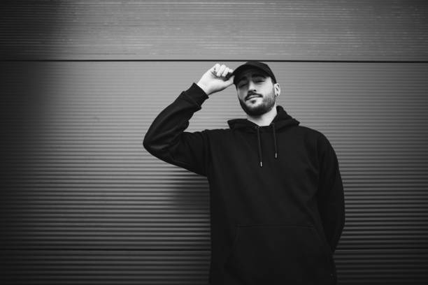 istock Young man standing in front of metal wall and looking at camera 1303885704