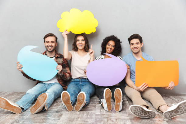istock Happy group of friends holding speech and thoughtful bubbles. 1303887193