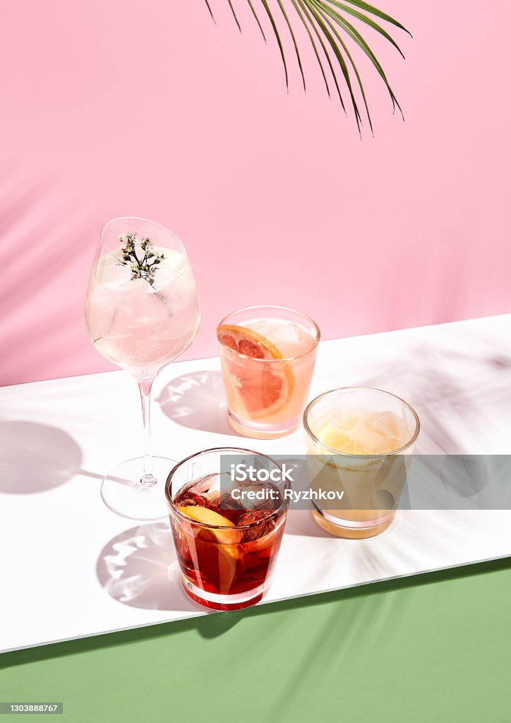 Sommercocktail mit Obst und Eis. Trinken Sie auf weißem Tisch über rosa Wand im Sonnenlicht mit Palmblatt Schatten. Sommer-, Tropisches, frisches Cocktailkonzept - Lizenzfrei Cocktail Stock-Foto