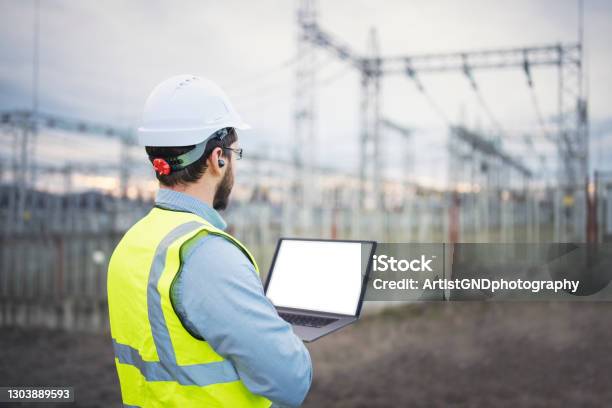 Portrait Of Confident Male Engineer Using A Laptop In Front Of Electric Power Station Stock Photo - Download Image Now