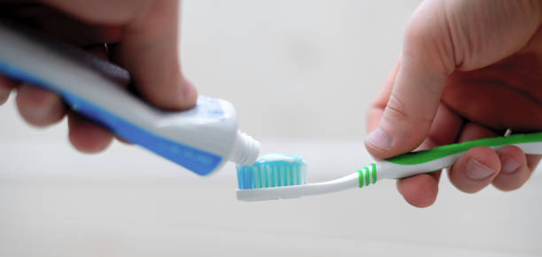 istock person squeeze toothpaste on a toothbrush in bathroom 1303890122