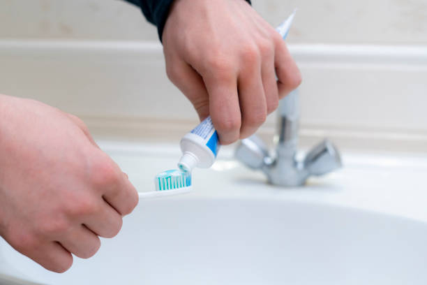 istock person squeeze toothpaste on a toothbrush in bathroom 1303890123