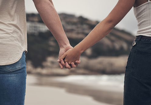 Cropped shot of an unrecognisable couple holding hands on the beach