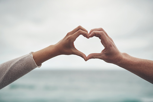 Cropped shot of a couple forming a heart shape with their hands