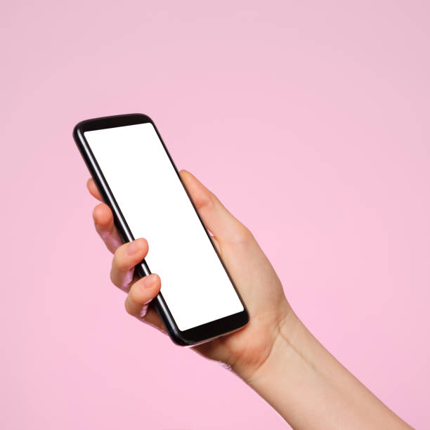 istock Smartphone with a blank screen in a woman's hand on a pink background. 1303892802