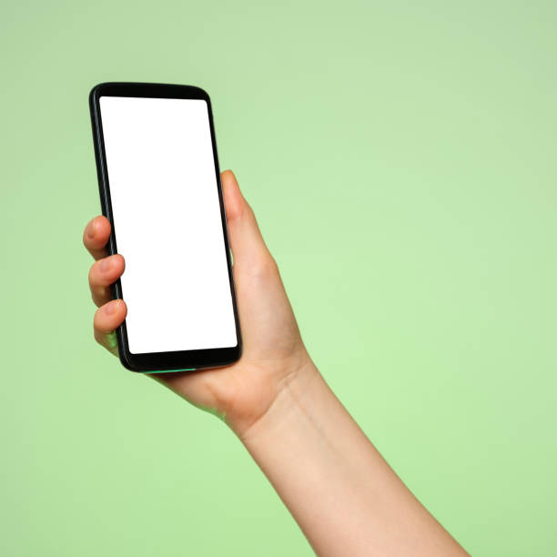 Smartphone upright with a blank screen in a woman's hand on a green background. Smartphone upright with a blank screen in a woman's hand on a green background. good posture photos stock pictures, royalty-free photos & images