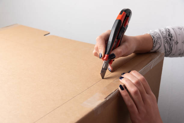 istock Hands holding craft knife for cutting carton box 1303897603