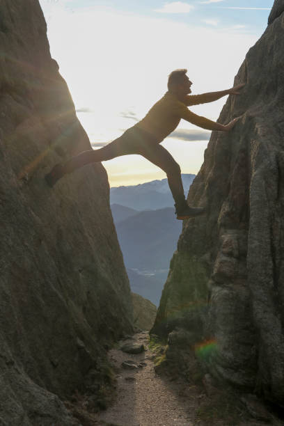 istock Man bridges gap in steep rock face 1303897845