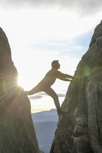 istock Man bridges gap in steep rock face 1303897851