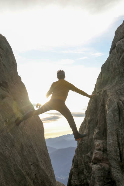 istock Man bridges gap in steep rock face 1303897867