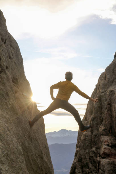 l’homme comble l’écart dans la face raide de roche - mountain climbing rock climbing motivation awe photos et images de collection