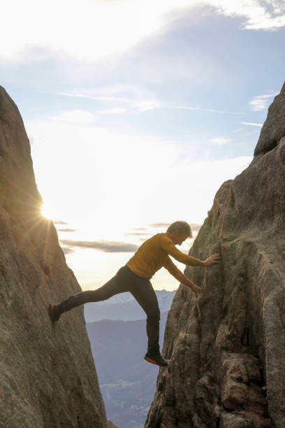 istock Man bridges gap in steep rock face 1303897888