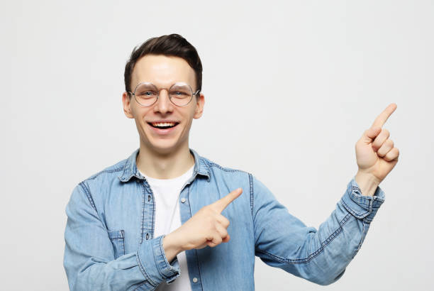 istock Positive man looks and points at upper right corner with both index fingers 1303900342