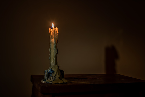 Fire candle stands on a wooden table in the dark