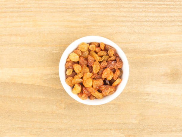 istock Raisins in a white bowl on brown wooden background 1303901616