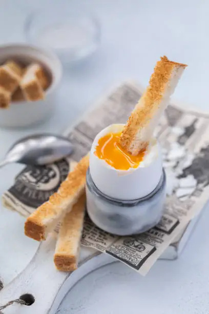 Soft-boiled egg in an eggcup breakfast with toasts and coffee on the wooden background