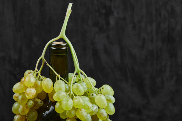 istock White grapes and a bottle of wine on dark background 1303902105