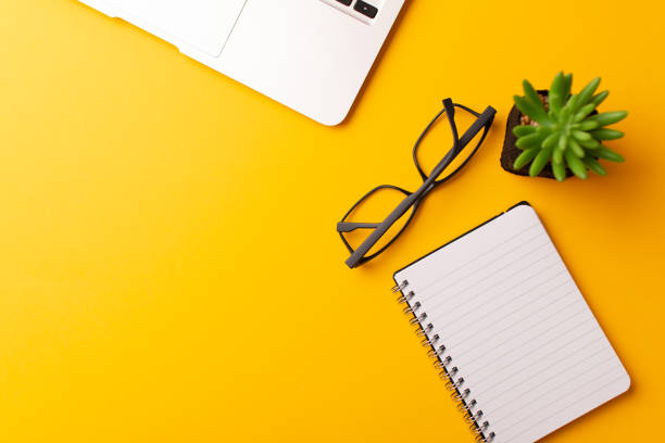 istock Top view of the workspace on yellow background 1303902984