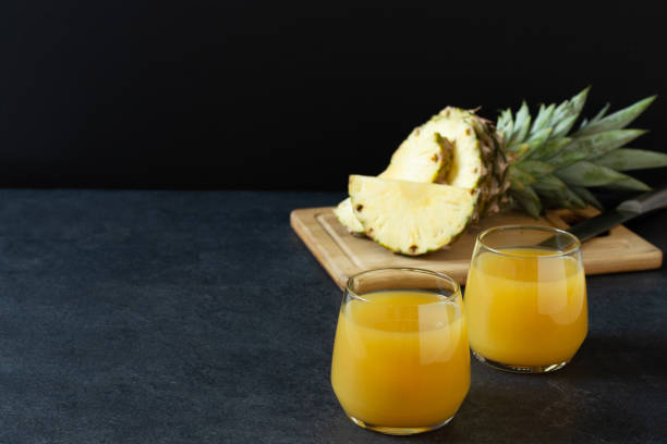 istock Pineapple fresh juice in glass on black table. 1303904490