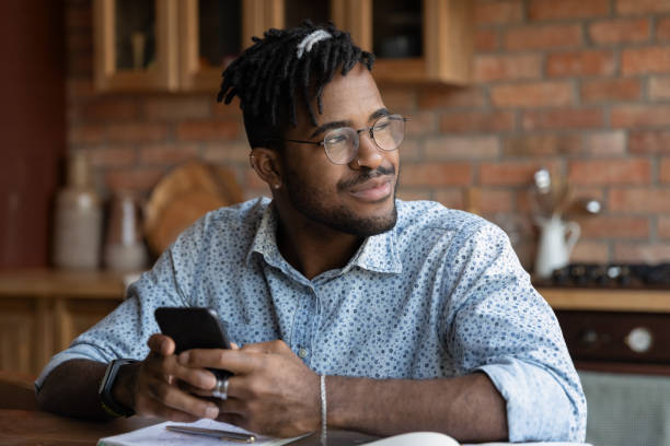 istock Close up dreamy African American man distracted from phone 1303905749
