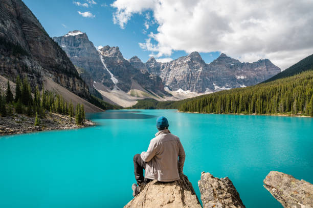 Hiker at Moraine Lake in Banff National Park, Alberta, Canada Hiker at Moraine Lake during summer in Banff National Park, Alberta, Canada. beautiful view of calgary canada stock pictures, royalty-free photos & images