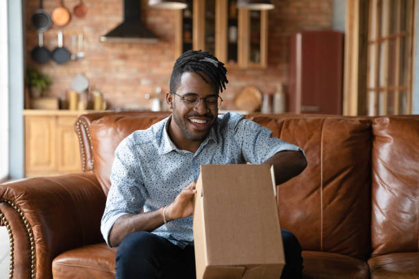 Close up excited African American man unpacking parcel at home