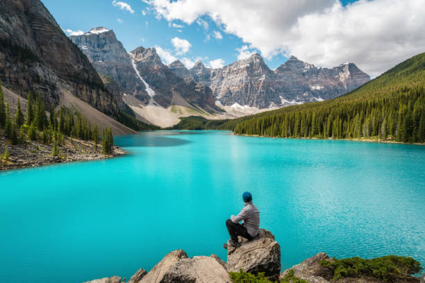 Hiker at Moraine Lake in Banff National Park, Alberta, Canada Hiker at Moraine Lake during summer in Banff National Park, Alberta, Canada. moraine lake stock pictures, royalty-free photos & images