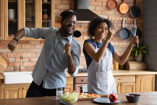 istock Close up overjoyed African American couple singing into kitchenware 1303905919