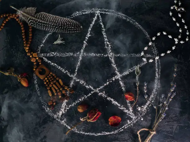 top view of the demon summoning ritual. a pentagram painted on a stone table , dried herbs and old ancient amulets
