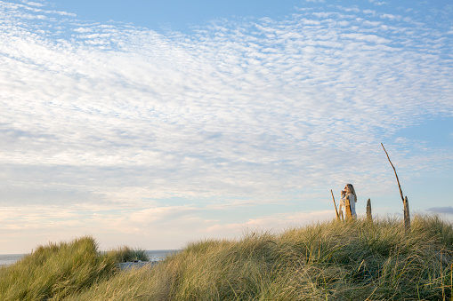 Rearview of a senior woman walking on the sand barefooted at Beadnell beach, North East England.