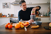 man preparing a fruit smoothie for breakfast at home