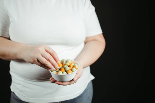istock Overweight woman overeating sugary snacks 1303910995