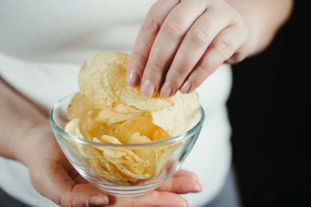 istock Dieting overweight woman eating potato chips 1303911009