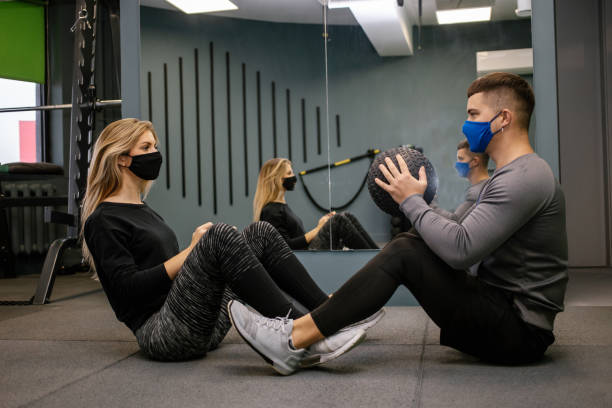 istock woman with protective mask in gym with trainer 1303911080