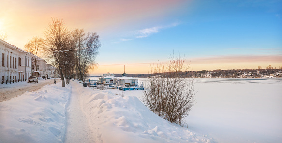 The Volga River embankment in Plyos in the snow in the light of the setting winter sun