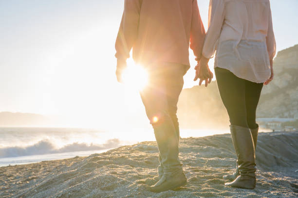 casal caminha ao longo da praia, ao nascer do sol - sunrise beach couple hiking - fotografias e filmes do acervo