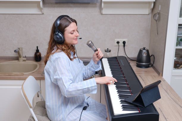 istock Happy woman singer smiles with a microphone in her hands on a home kitchen 1303912369