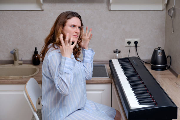 istock Woman angrily looks at home digital piano, problems learning to play musical instruments 1303912377