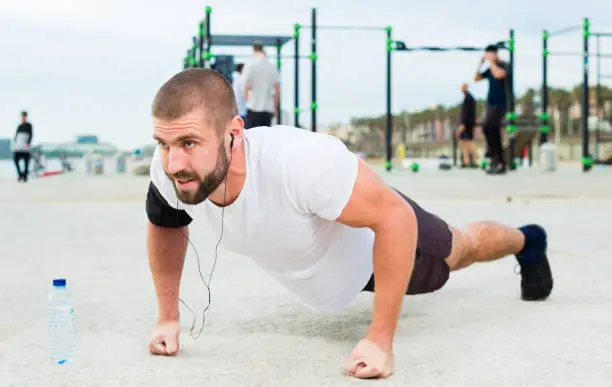 Strong man performs push-ups on an outdoor sports field