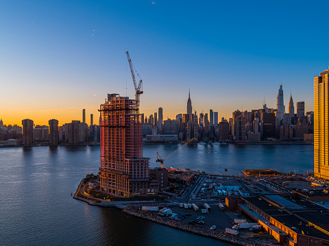 夜にはマンハッタンのスカイラインの美しい景色を望むクイーンズのウォーターフロントに新しい高級住宅タワーの建設 建設現場のストックフォトや