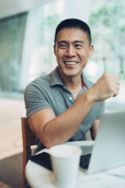 istock Smiling middle age man with a laptop in cafe 1303915064