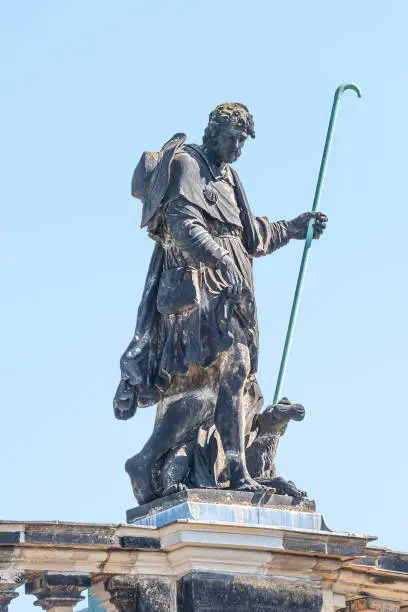 Photo of Old roof church statute of a pilgrim with stick and dog in historical downtown of Dresden, Germany, details, closeup.