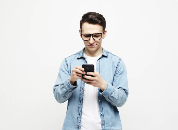 istock Happy young man in glasses typing sms on white background 1303916391