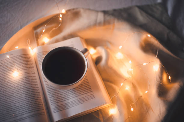 istock Cup of tea with book over lights 1303916449