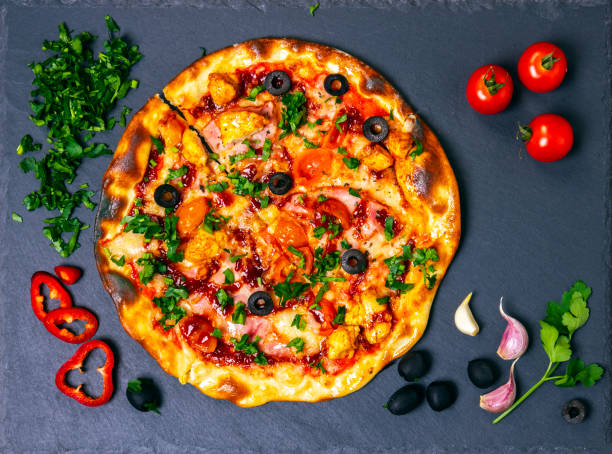 istock Pizza with ham and chicken on slate board. Flat layout, top view. 1303916864