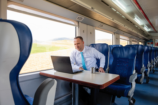 Businessman traveling in train and using laptop