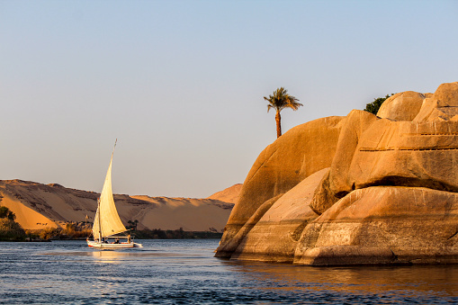 Aswan, Egypt - April 28, 2023: Passenger transport boat sailing in front of the Temple of Philae in the waters of the Nile River