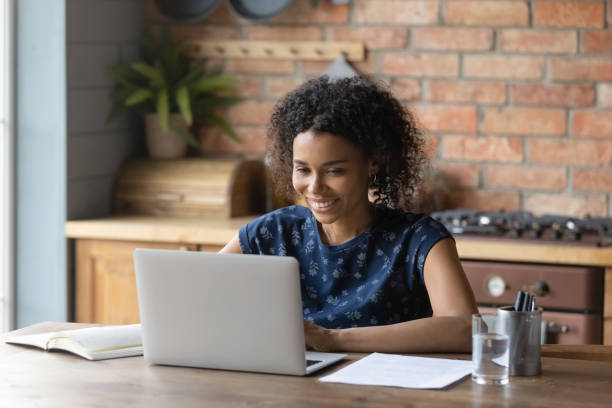 istock Close up smiling African American woman using laptop in kitchen 1303920874