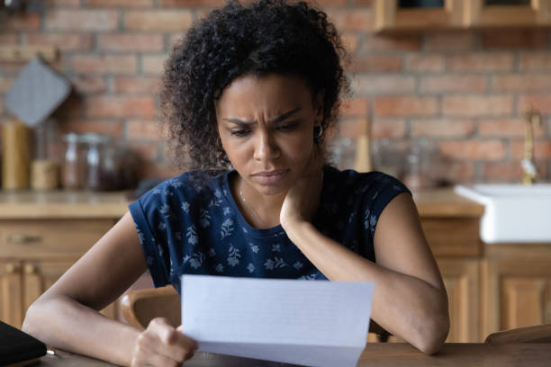 Close up unhappy African American woman reading letter, bad news Close up unhappy African American young woman reading letter, document, frustrated businesswoman or student received bad news, unexpected debt or job dismissal notification, financial problem scammer stock pictures, royalty-free photos & images
