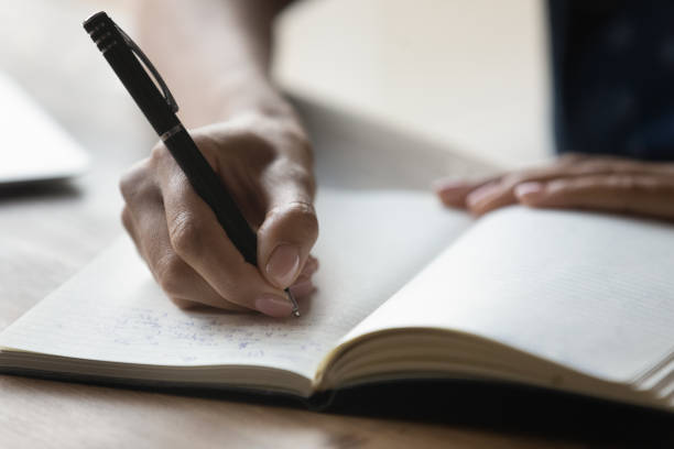 istock Close up African American woman taking notes, writing in notebook 1303920906